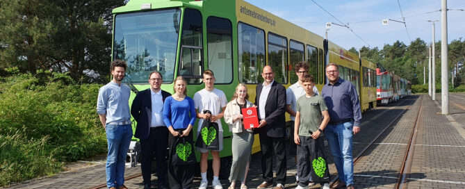 Schüler stehen vor einer Cottbuser Straßenbahn und übergeben Unterschriften