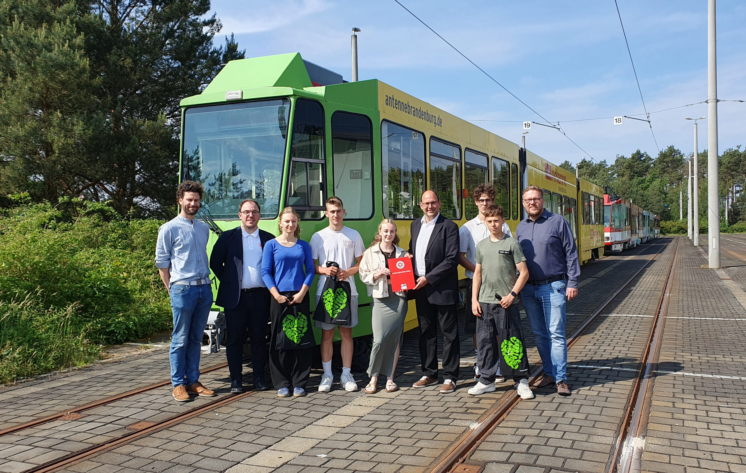 Schüler stehen vor einer Cottbuser Straßenbahn und übergeben Unterschriften