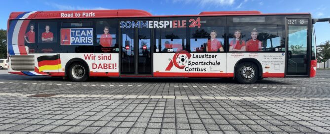 Das Foto zeigt einen Bus von Cottbusverkehr, der mit den Gesichtern der Olympia-Teilnehmer bedruckt ist.