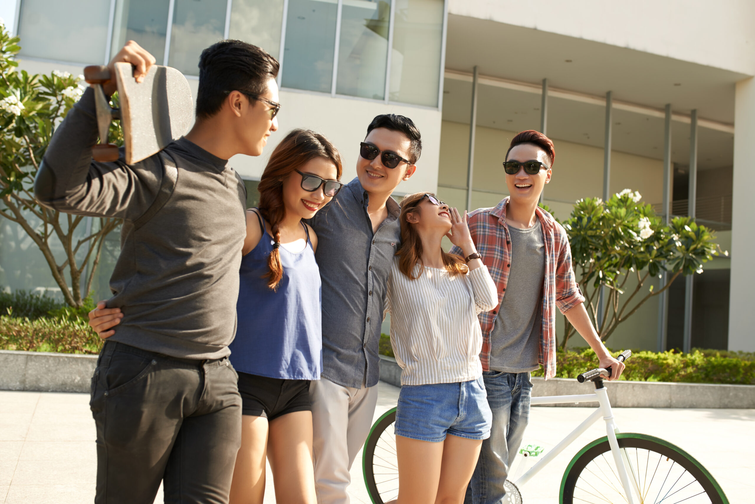 Junge Leute unterwegs im Freien mit Fahrrad und Skateboard.