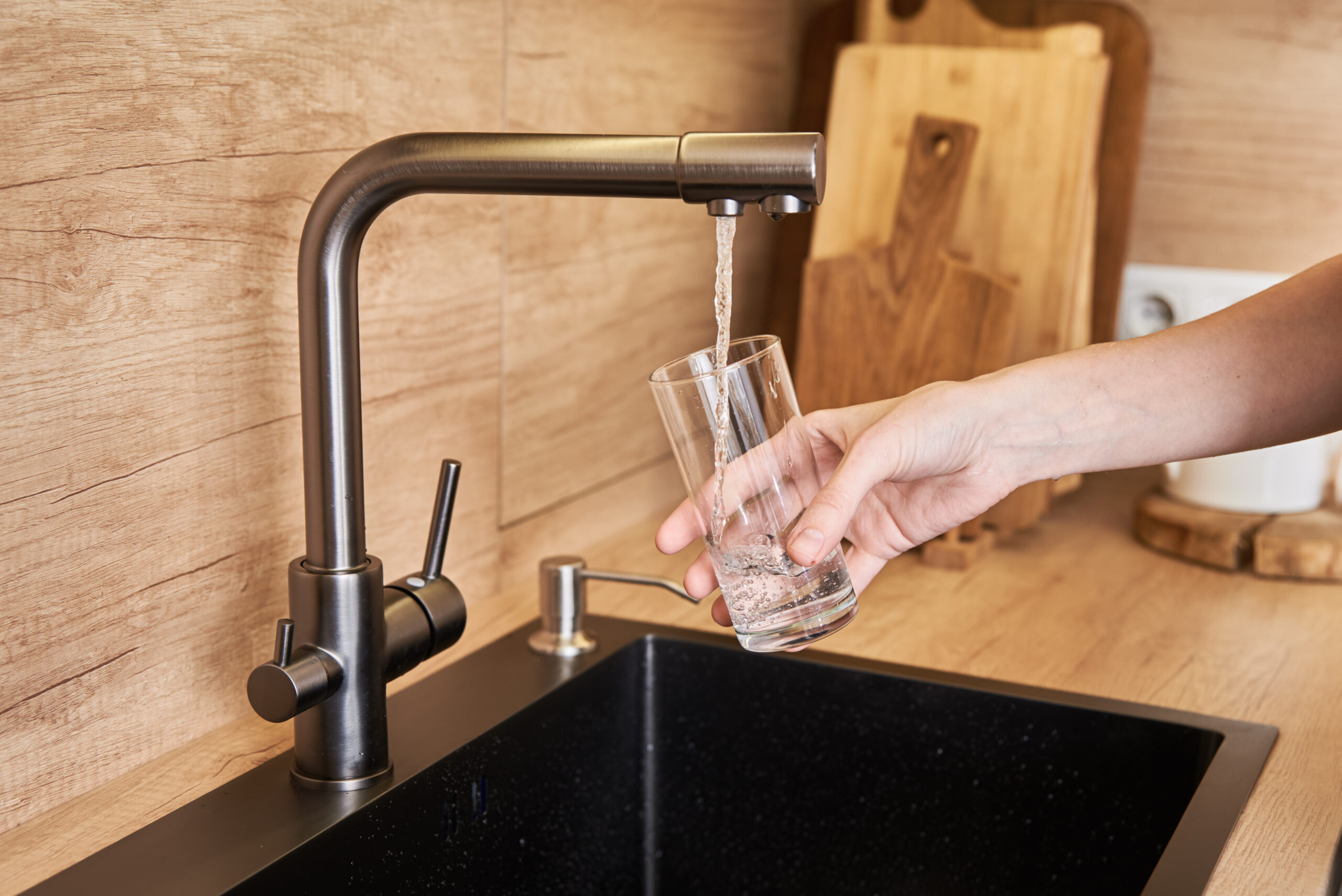 Ein Glas wird am Hahn mit Trinkwasser gefüllt.